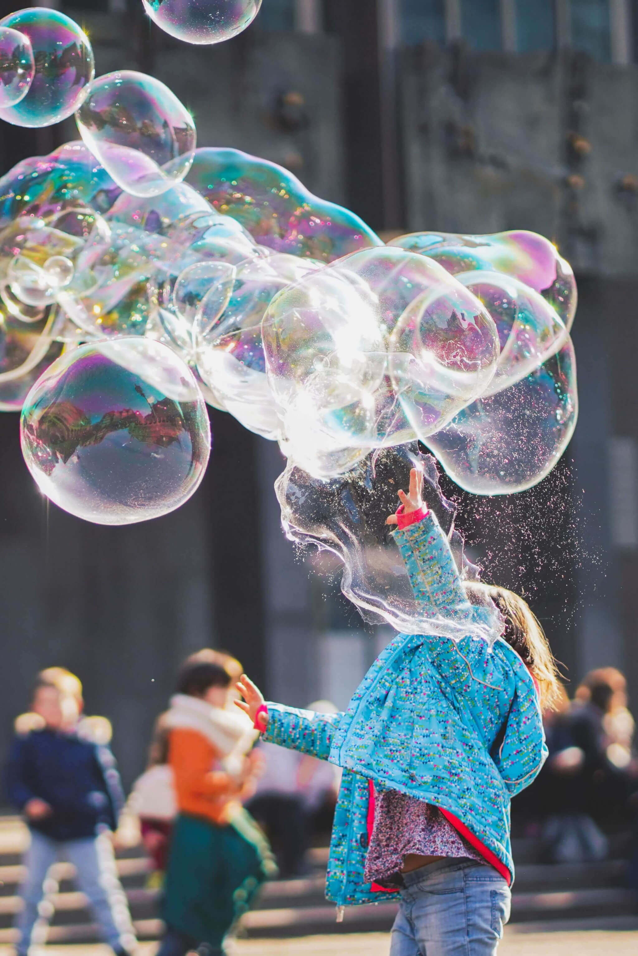The girl is trying to catch soap bubbles.